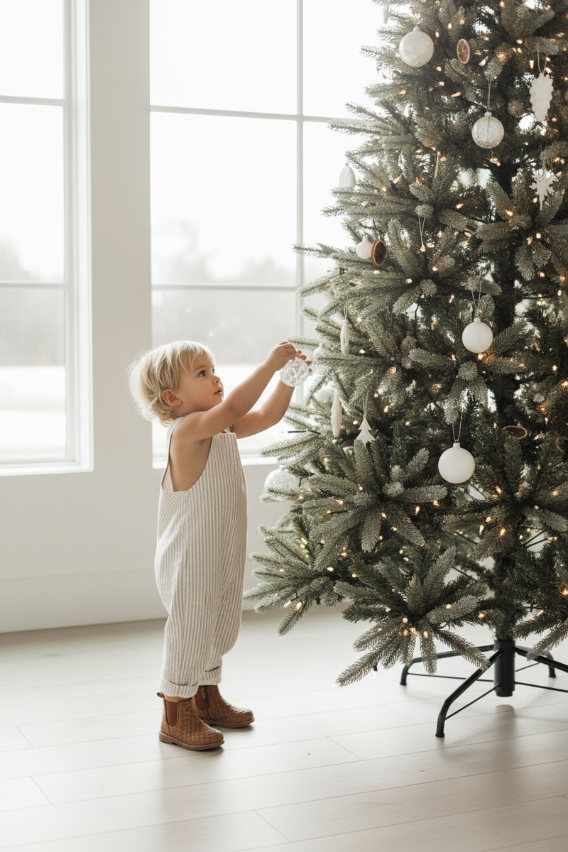 Boy hanging ornament in Grady romper