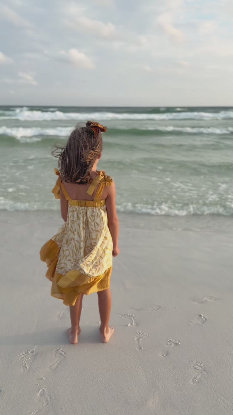 SS Girl's Dress Evie Tunic Dress (golden fields). Girl wearing Indie Blue Evie Tunic Dress golden field pattern walking on the beach