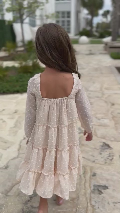 Video of girl wearing Indie Blue Nora Dress in Natural Swiss Dot walking on paved walkway near the beach