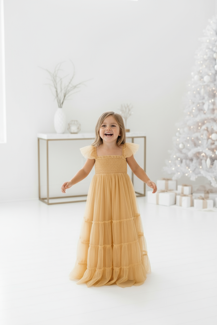 Toddler laughing naturally in white holiday setting with Marabella saffron dress